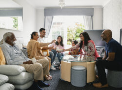 A wide-view shot of a family all sitting with each other socialising and having snacks.